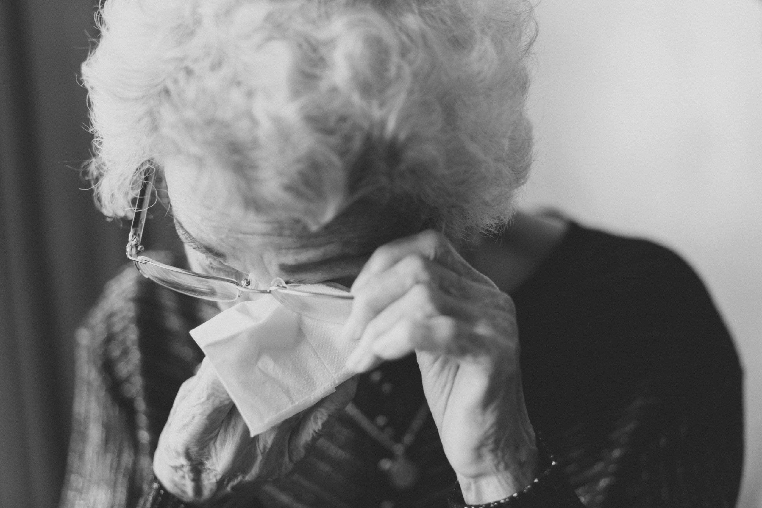 an elderly woman wiping her eyes with a tissue
