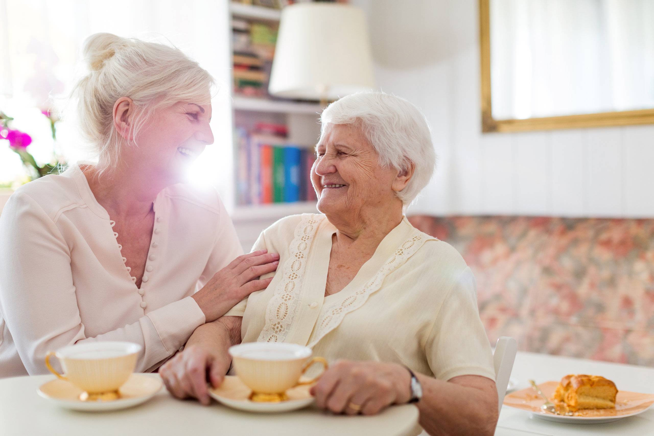 senior woman and her caregiver drinking coffee