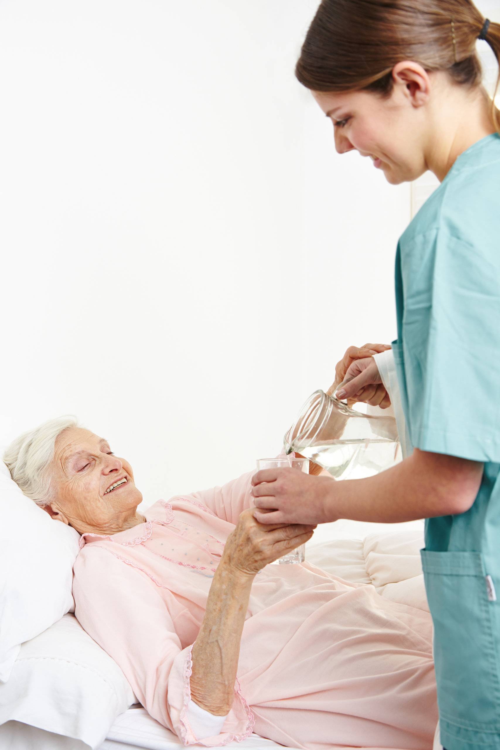 a nurse giving water to an elderly woman laying on bed